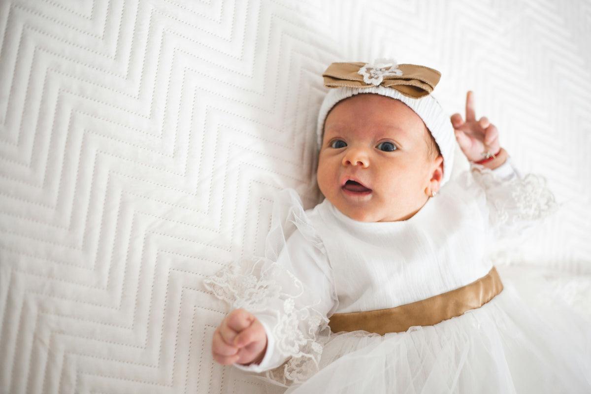 Bébé en tenue blanche de baptême avec détails dorés